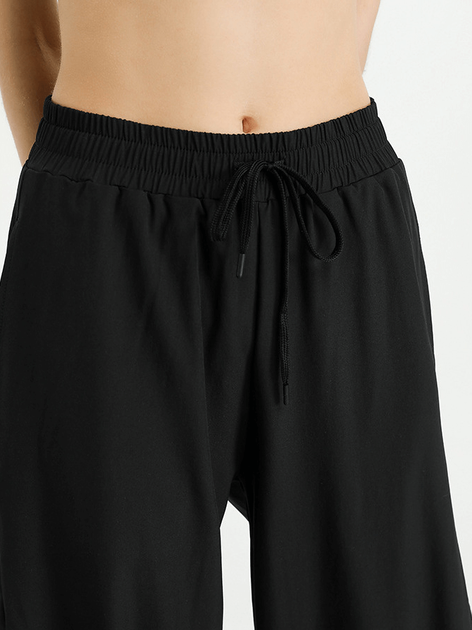 Woman wearing mesh drawstring running trousers, ideal for yoga, with black elastic waistband, showcasing comfort and flexibility.